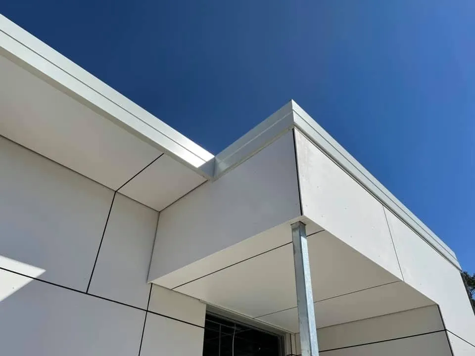 White flat-panel cladding and fascia against a blue sky
