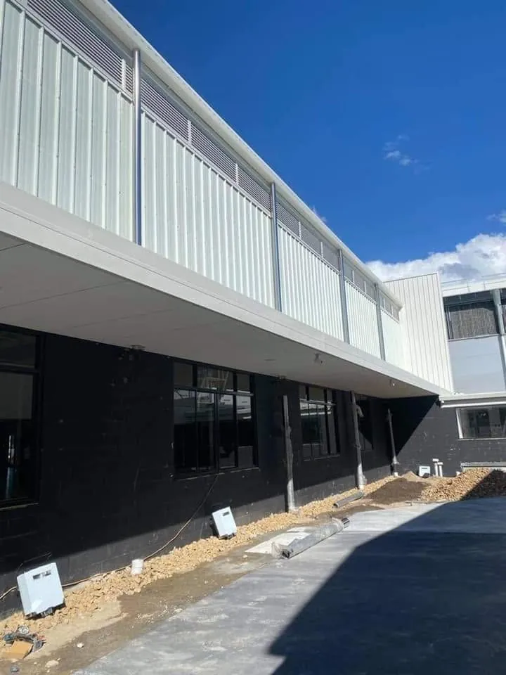 White vertical cladding above a covered walkway at a school