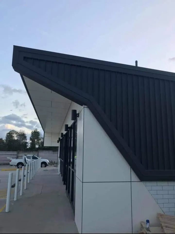 Angled black standing seam canopy on a service station