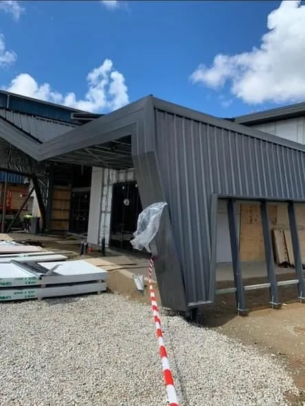 Folded grey standing seam entry canopy under construction