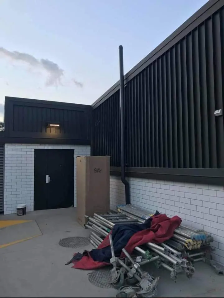 Black vertical cladding and fascia above white brickwork